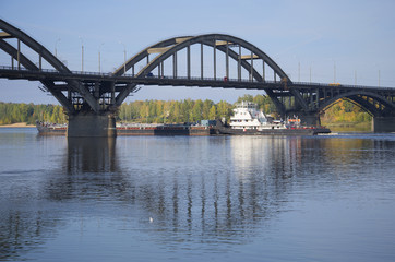 Речной буксир с баржей проходит под автомобильным мостом. Рыбинск