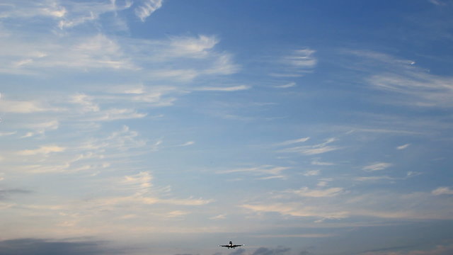 Large jet airplane is flying over runway approach lights at the airport of Schiphol at dusk.
