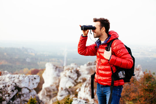 Ypung man with backpack looking through binoculars