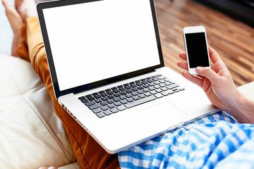 Laptop and smartphone mockup. Closeup of man holding laptop on his knees and smartphone in hand