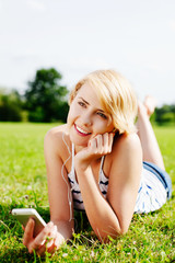 Young blond woman listening to mp3s in the park