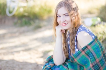 Fototapeta premium Beautiful happy woman with long hair on the nature, covered blanket 