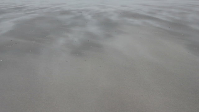 Sand blowing over a beach on a windy day.