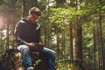 Young man using a digital tablet in the woods