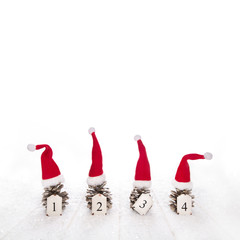 Vier Tannenzapfen mit roten Weihnachtsmützen mit Zahlen als Dekoration zu Weihnachten.