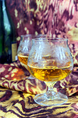 Two glasses of cognac with bottle on a colored background