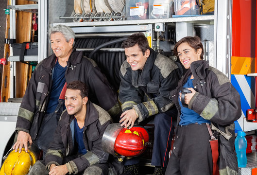 Team Of Happy Firefighters By Firetruck