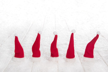 Fünf rote Nikolaus Mützen als Dekoration zu Weihnachten mit Schnee.