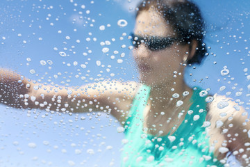 Blurred woman washing car window, soap bubbles, view from inside.