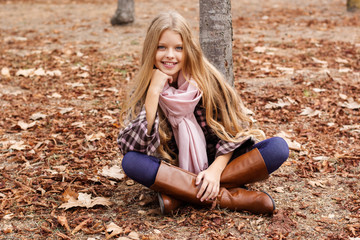 Obraz premium Young girl is sitting on autumn foliage