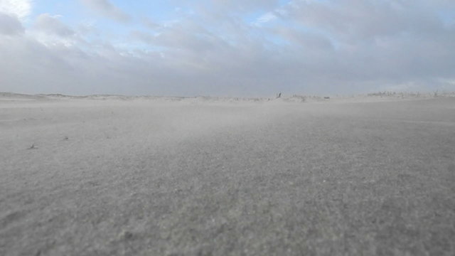 Sand blowing over a beach on a windy day.