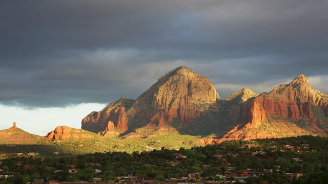 Pan of Sedona, Arizona just after sunrise on a stormy morning, with red rock formations in the background.