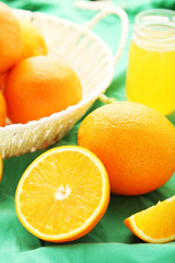 Ripe oranges in basket on green background