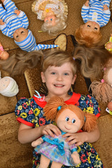 portrait of little girl(child, kid) with dolls on the carpet