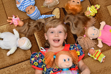 portrait of little girl(child, kid) with dolls on the carpet