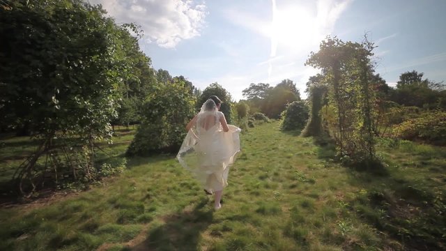 Bride running in the park in the sunlight fly-cam