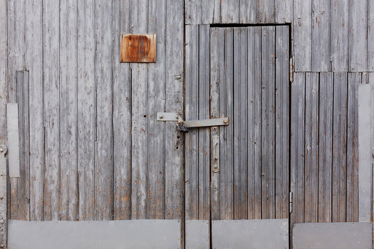 Old grey wood locked door on grunge grey wall