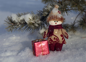 Toy  snowman with a gift on the snow
