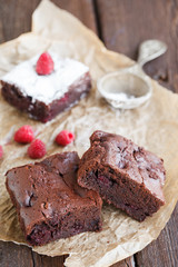 Chocolate brownie with raspberries, sprinkled with powdered sugar.