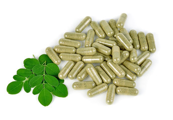 herb capsule with green herbal leaf isolated on white background