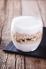 Breakfast with muesli, yogurt in a glass on a wooden background. selective focus