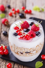 Breakfast with muesli, yogurt,honey and fresh berries in a glass on a wooden background. selective focus