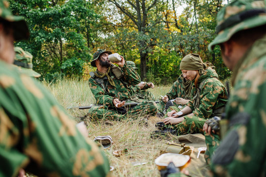 soldiers team are heated food on the fire and eat in the forest