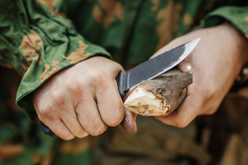soldier with a knife cut a wooden stick