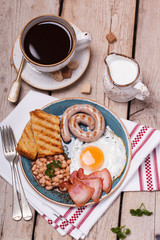 English breakfast with fried eggs, bacon, sausages, beans, toasts. selective focus.