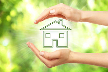 Hands holding eco house icon on nature background