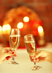 Clinking glasses of champagne in hands on bright lights background