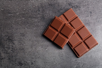 Milk chocolate pieces on gray background