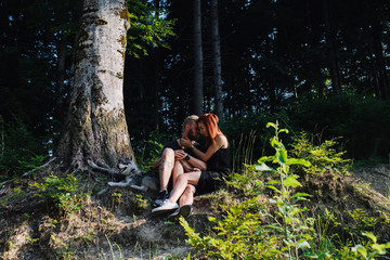 beautiful couple sitting in a forest near the tree