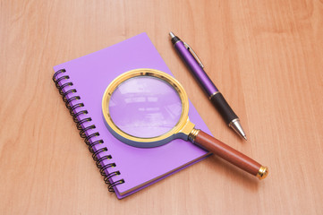 notebook pen and magnifying glass
