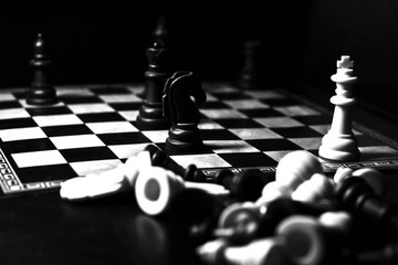 Chess pieces in a war on chess board on black background.