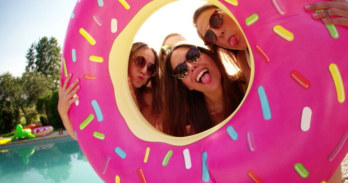Group of friends holding a pool inflatable like a frame