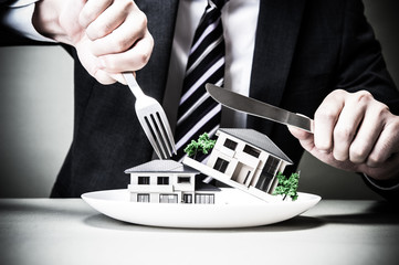 ナイフとフォークで家を食べようとしているビジネスマン