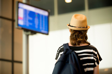 Woman looking at airport flight information board