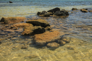 Rocks on the beach, rocks and beach during sunny day on blue sky and sea