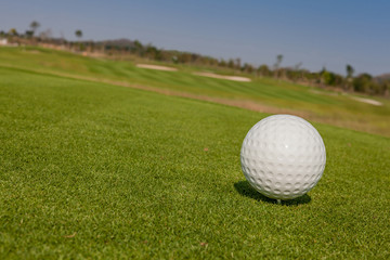 The view of macro golf ball and the green golf course background