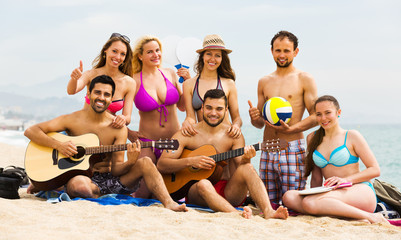 Friends with guitar at beach .