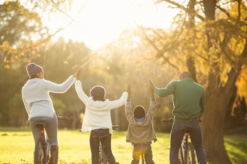 Rear view of a young family with arms raised on bike