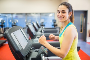 Fototapeta na wymiar Smiling woman running on a treadmill
