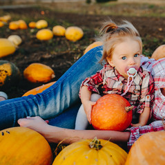 mother and daughter lie between pumpkins