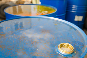 Fuel oil barrels close view of nozzle with watter on them and rust starting to eat through the blue metal container suggesting toxic pollution, biohazard and ecology problems