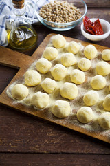 Uncooked homemade potato gnocchi and strainer on vintage cutting