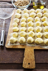 Uncooked homemade potato gnocchi and strainer on vintage cutting