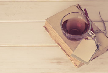 Old book with decorative greeting card, nib pen and cup tea