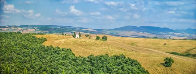 Naklejka premium Scenic Tuscany landscape with rolling hills and golden harvest fields and famous Cappella della Madonna di Vitaleta in Val d'Orcia, Italy