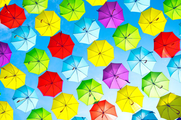 Fototapeta na wymiar Colorful umbrellas urban street decoration. Hanging Multicolored umbrellas over blue sky